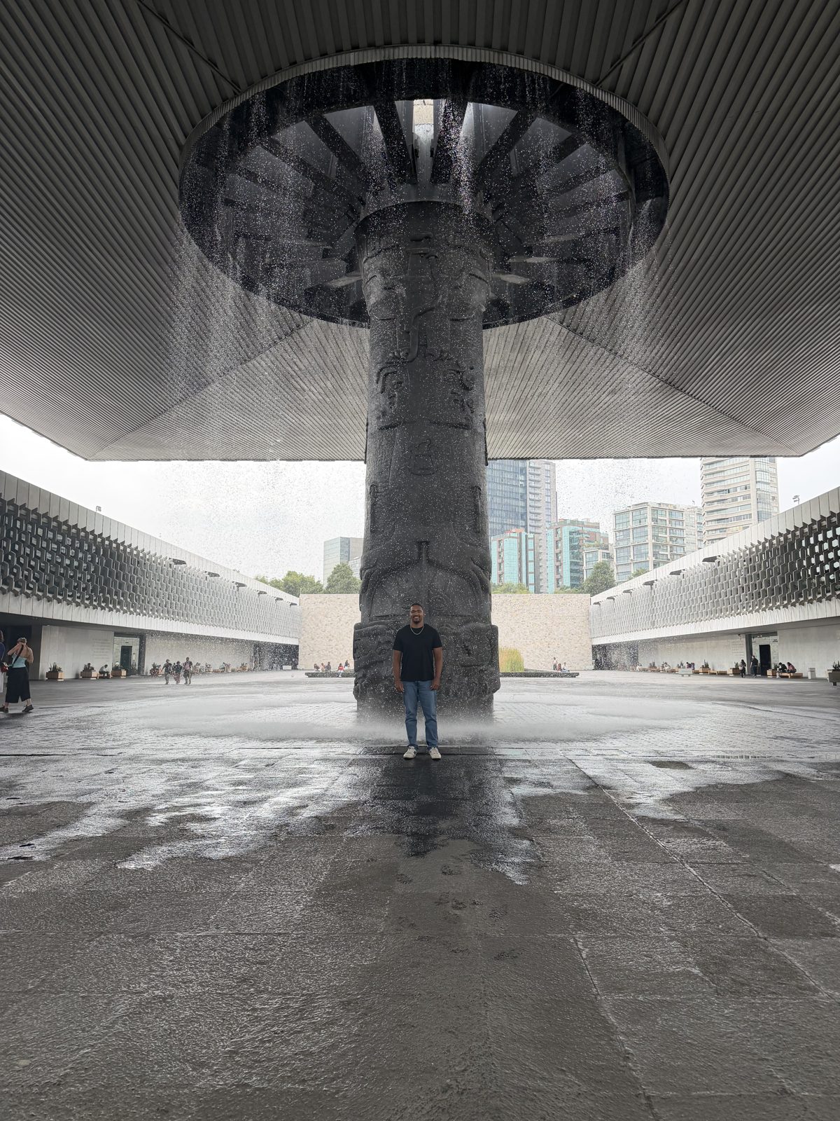 Standing still under a curtain of falling water in a museum courtyard, Mexico City